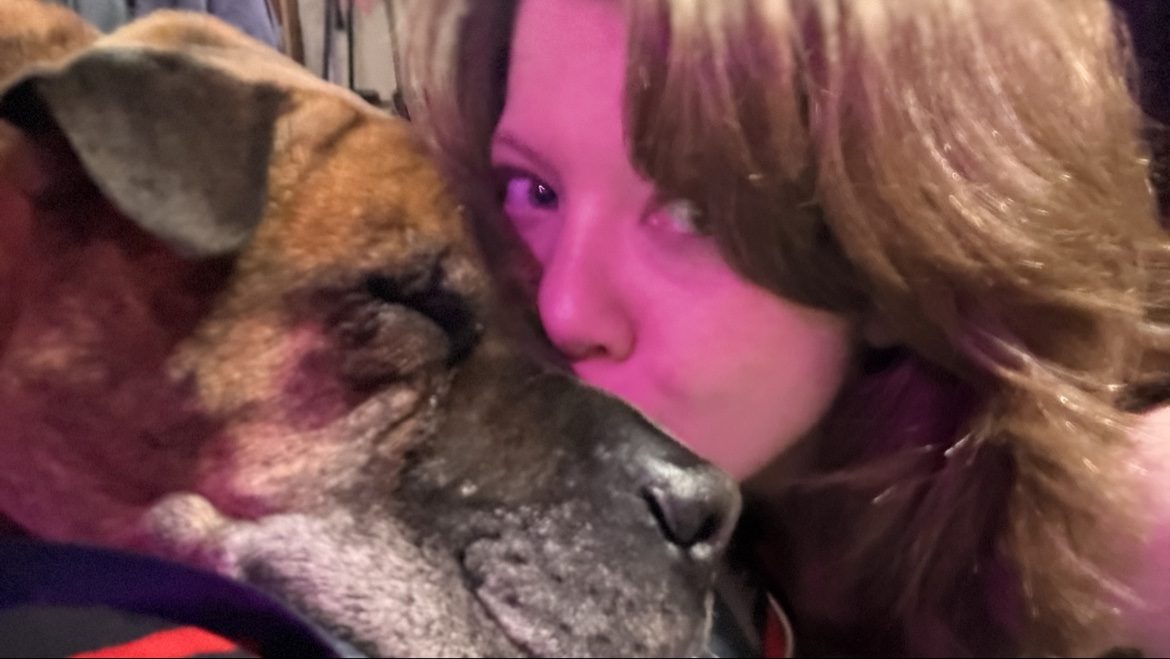 Em kissing the grey muzzle of Bane, her thirteen-year-old brindle dog